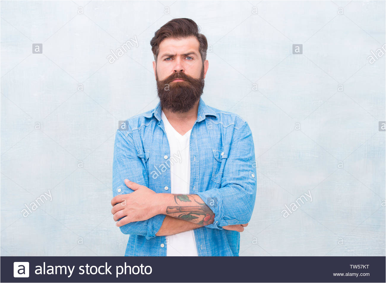 masculinity and male beauty concept hipster with beard and mustache wear denim shirt well groomed macho brutal handsome hipster man on grey wall background bearded man trendy hipster style tw57kt jpg