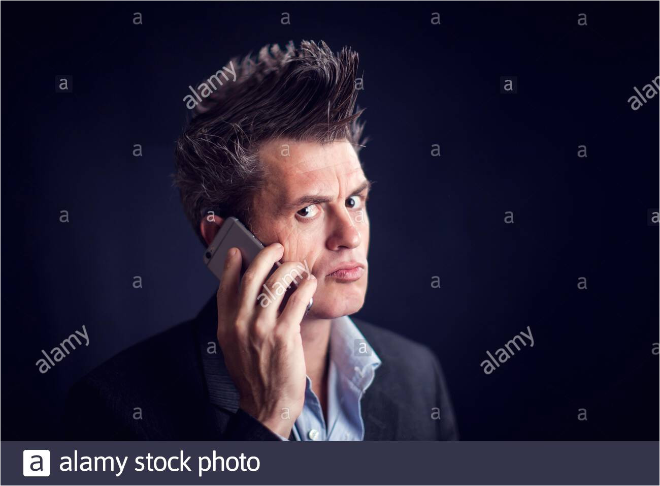 handsome man with mohawk wearing suit using mobile phone in front of black background 2agr9h9 jpg