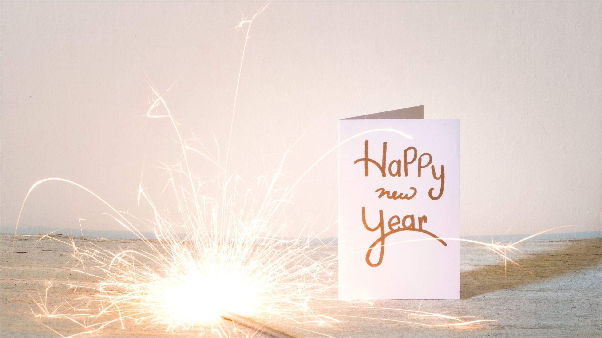 new year card with lit sparkler on table against wall 688969401 5bd668bc46e0fb0026718605 jpg