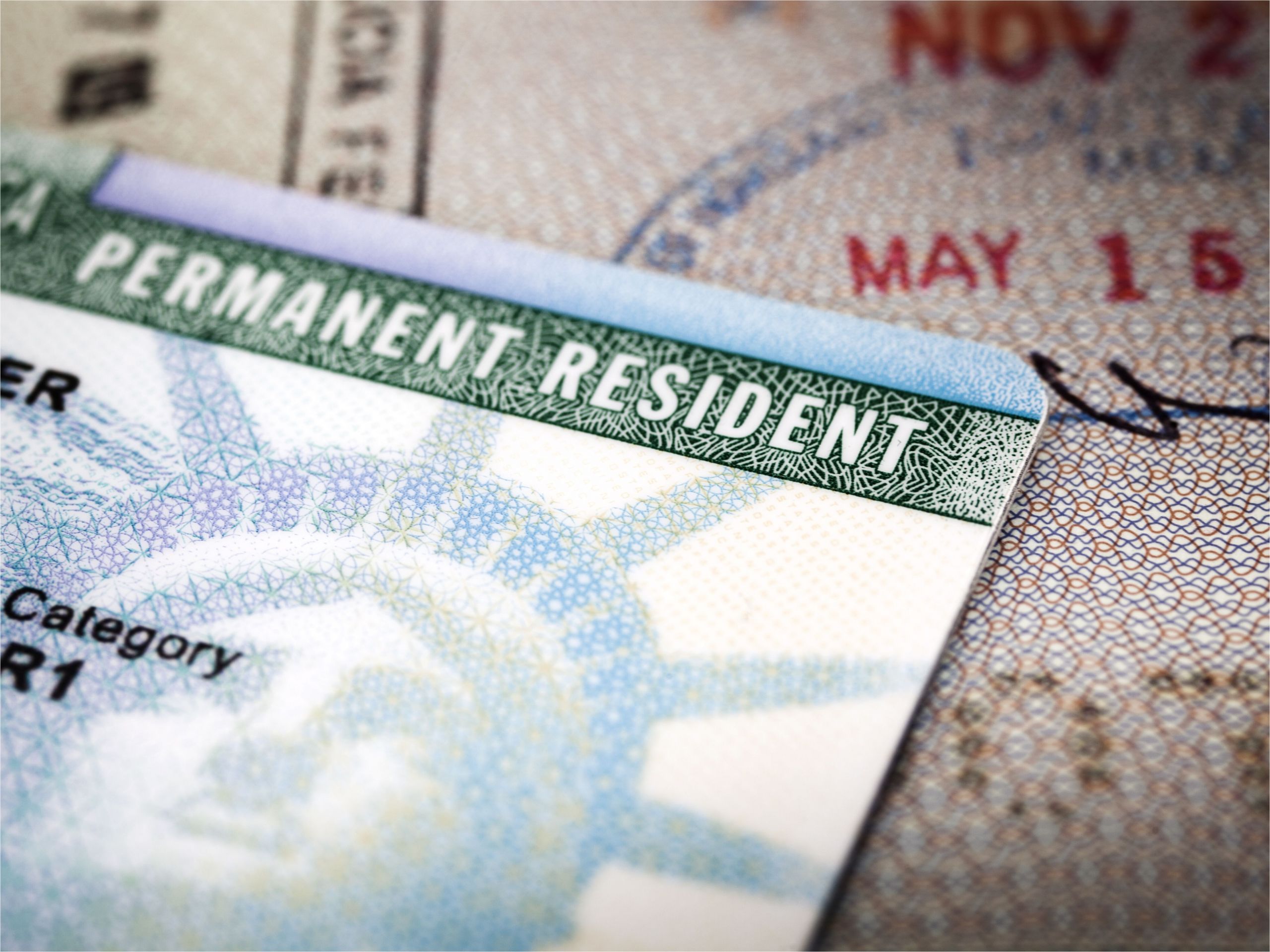 a green card lying on an open passport close up full frame 187591458 5aa6c5caa9d4f900369f3d3d jpg