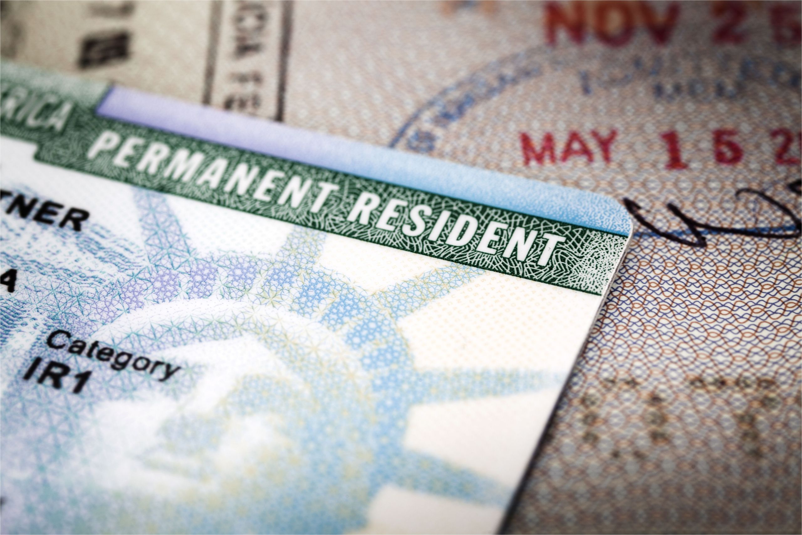 a green card lying on an open passport close up full frame 187591458 5aa6c5caa9d4f900369f3d3d jpg